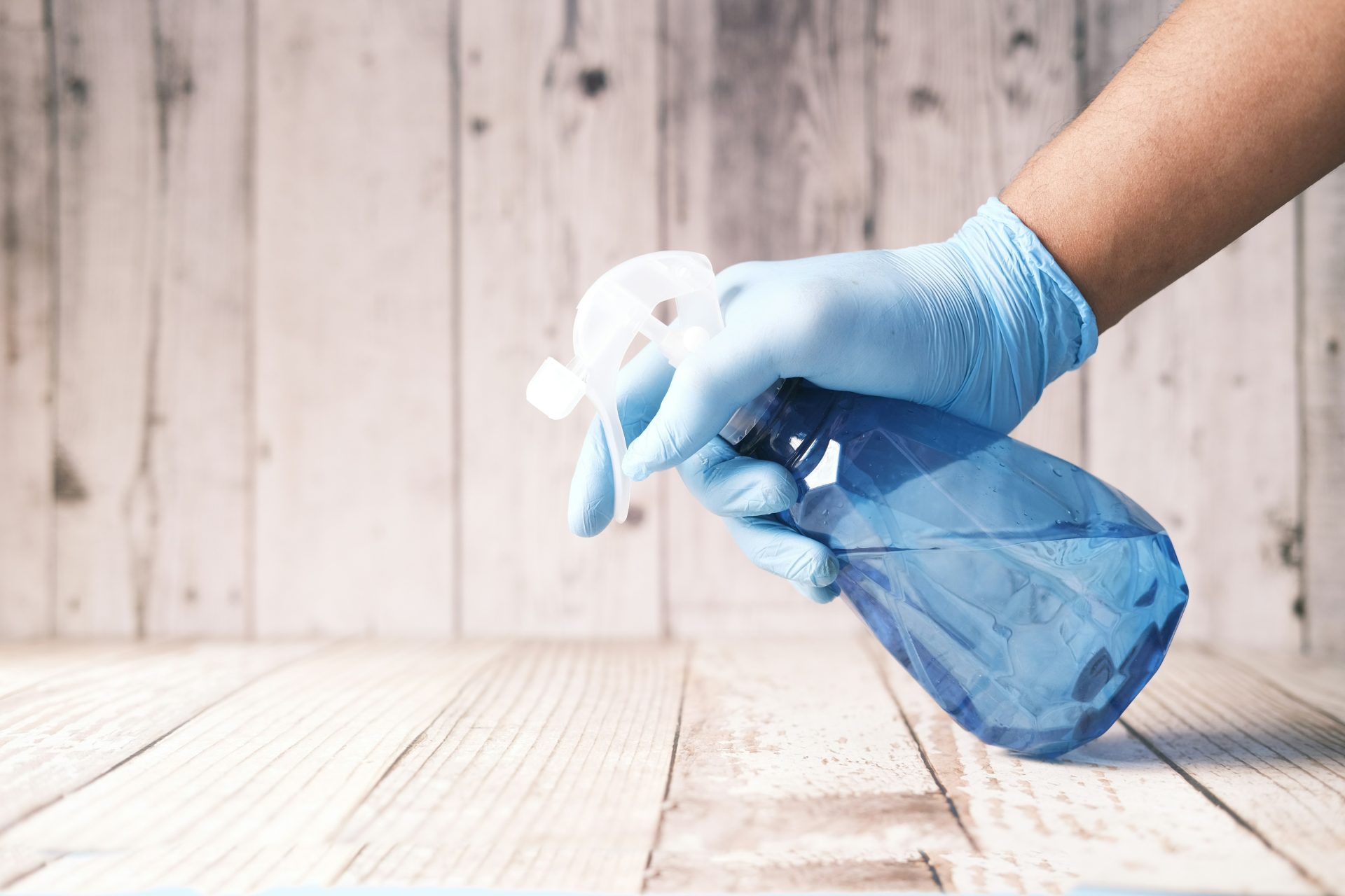 Gloved hand spraying blue cleaning solution